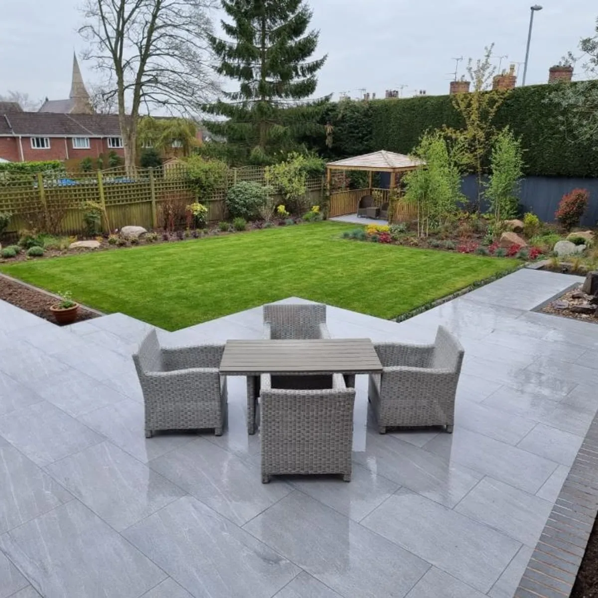 A porcelain patio and lawn in a landscaped garden by JR Landscapes & Driveways