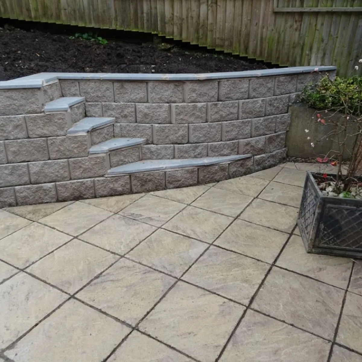 Block retaining wall with steps and a paved terrace