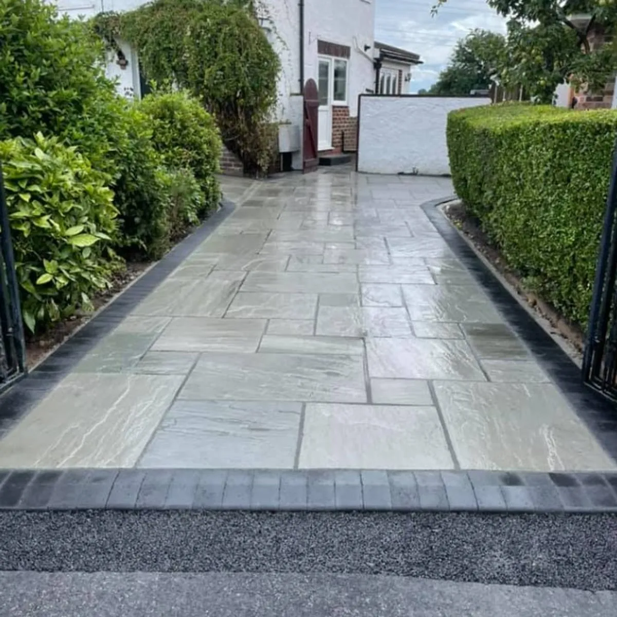 Large format grey paving path between hedges